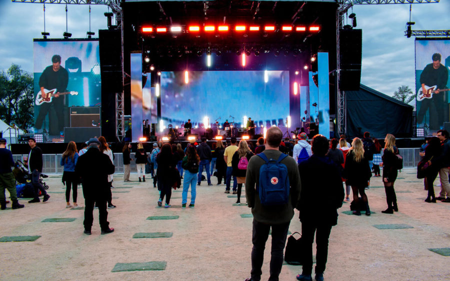 A half empty field of festivalgoers watch a band on stage.